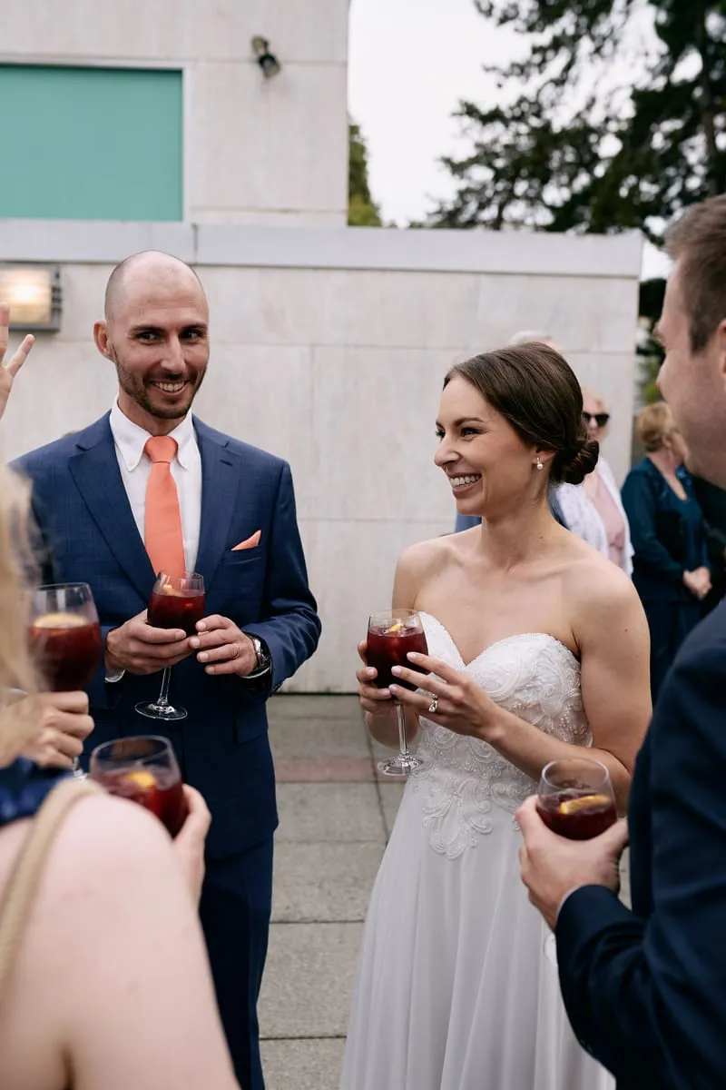 Olivia and James laugh with guests, glasses of red sangria in their hands.