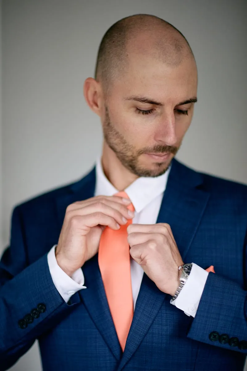 James in his blue checked jacket, straightening the coral tie with both hands.