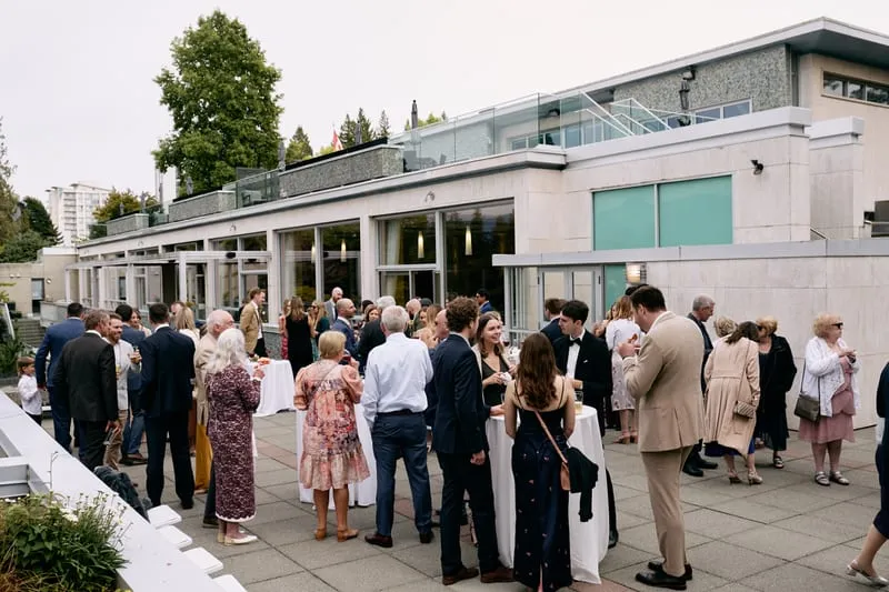 Guests mingle on the terrace outside the long glass-fronted building.