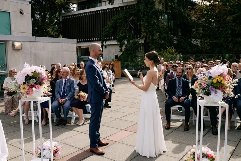 Olivia reads from a small book to James between two tall stands of flowers.