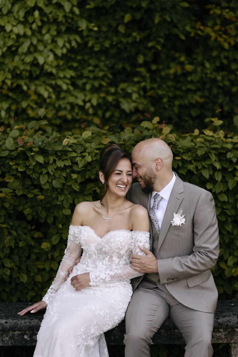 Couple embracing in a chateau garden, photographed from a distance.