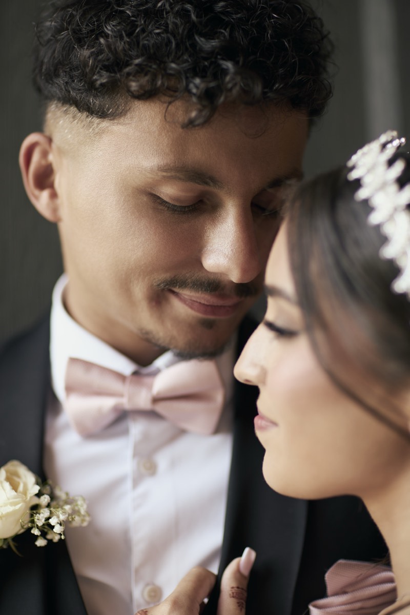 Black and white portrait of a bride and groom among tall hedges.