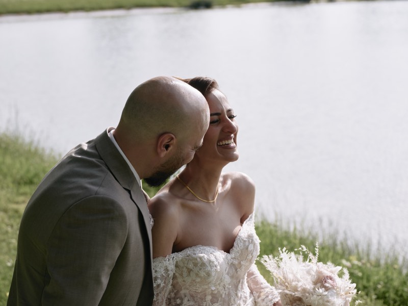 Bride and groom walking a tree-lined avenue in formal gardens.
