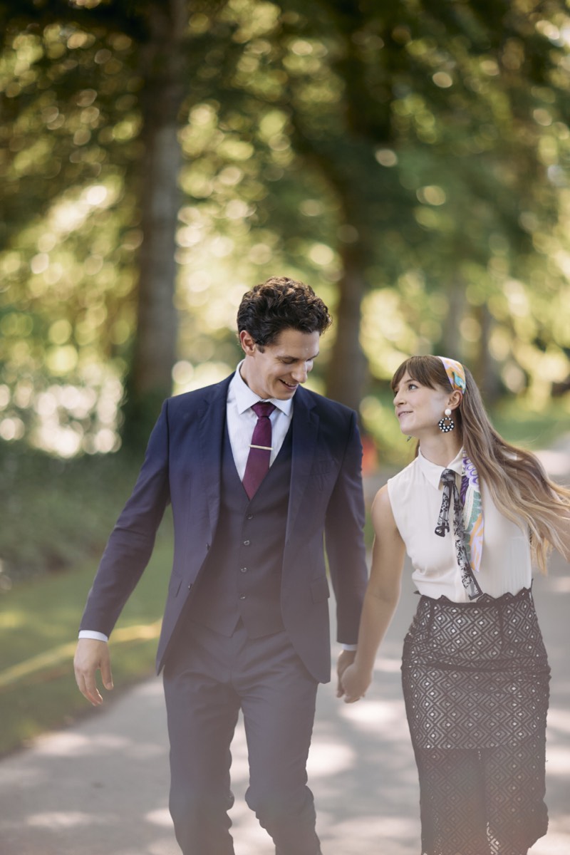 Black and white portrait of a bride and groom among tall hedges.