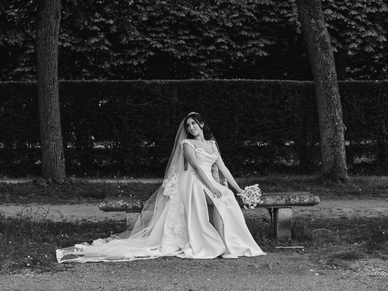 Bride in a lace gown holding her bouquet on a garden path.