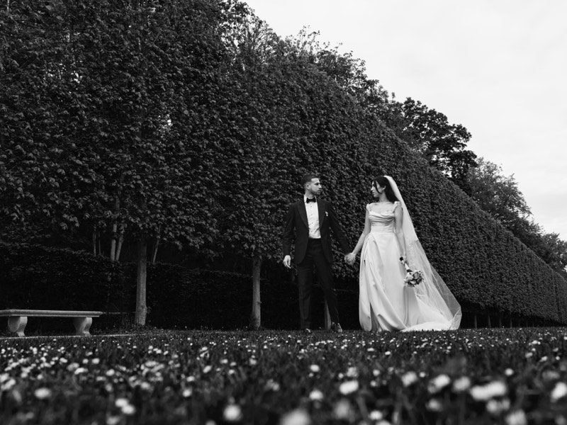 Couple embracing in a chateau garden, photographed from a distance.