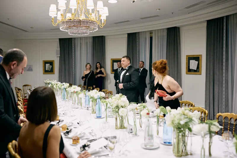 White flowers in glass vases along the reception table, with a guest in a black dress at the edge of the frame.